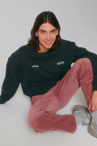 Person wearing a black sweatshirt and red pants sitting on a white floor.