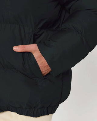 Close-up of a person wearing a black puffer jacket with a neutral background