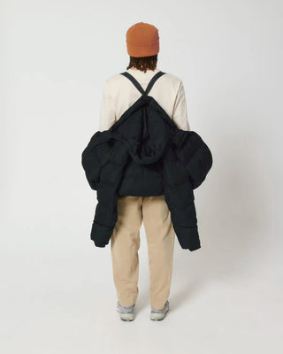 Person wearing a black puffer jacket with straps on a white background